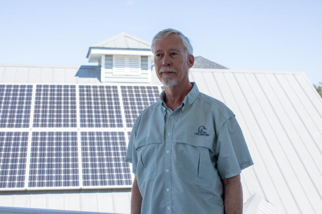 Jim Muhl stands on his porch with his solar power system behind him. 