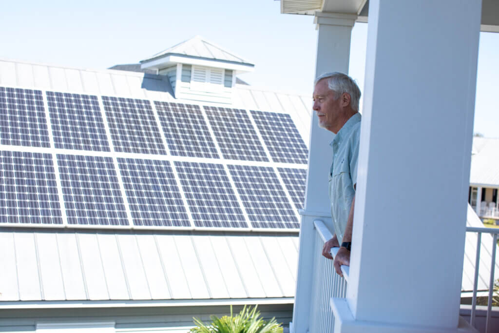 Jim Muhl stands on his porch with his solar power system behind him. 