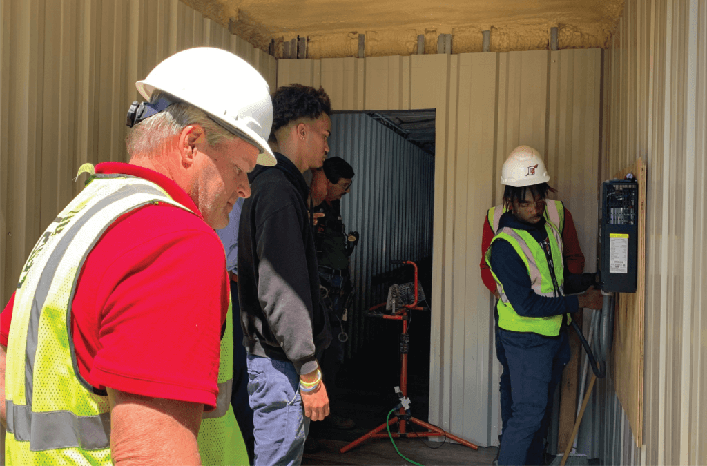 Chickasaw students install the electrical panel inside the container classroom. 